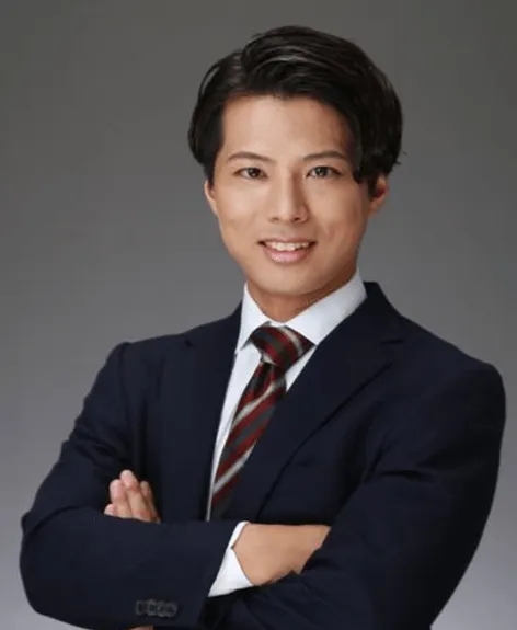 ネイビーのスーツを着て腕を組んで微笑んでいるアジア系の男性のポートレート。