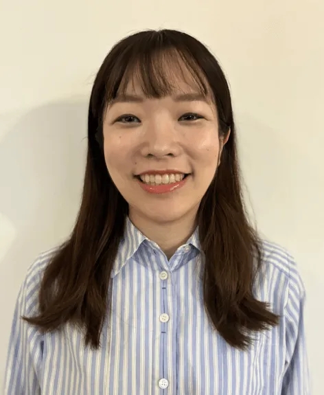 笑顔の女性のポートレート。彼女はストライプのシャツを着ており、カメラに向かって微笑んでいます。