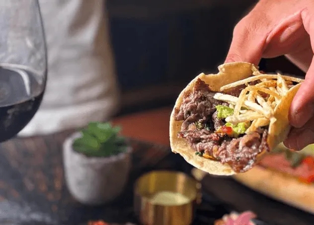 手で持たれたタコスのクローズアップ写真。