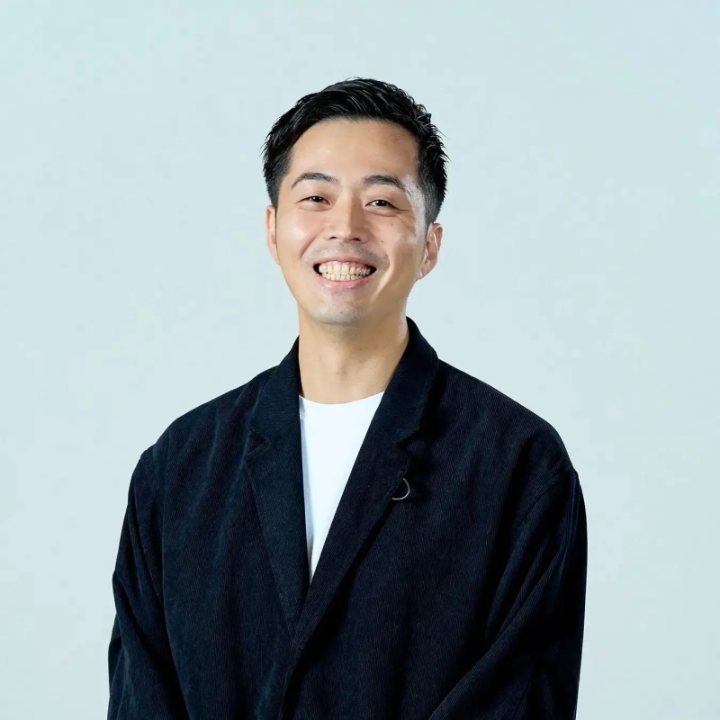 笑顔の男性のポートレート。彼は黒いジャケットと白いTシャツを着ていて、背景は白です。