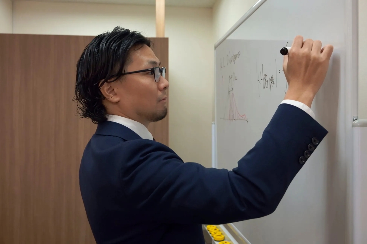 ホワイトボードに数式を書く男性