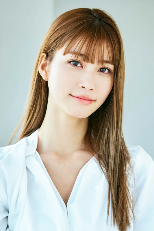 女性のポートレート。長い茶色の髪で、白いシャツを着ています。背景は明るい。